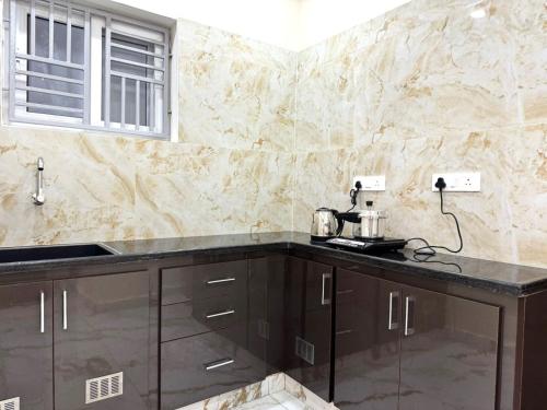a kitchen with brown cabinets and a counter top at Urban Nest Homestay in Tirupati