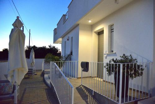 a white house with a balcony with a plant at B&B Domus Terra Mare in Torre San Giovanni Ugento