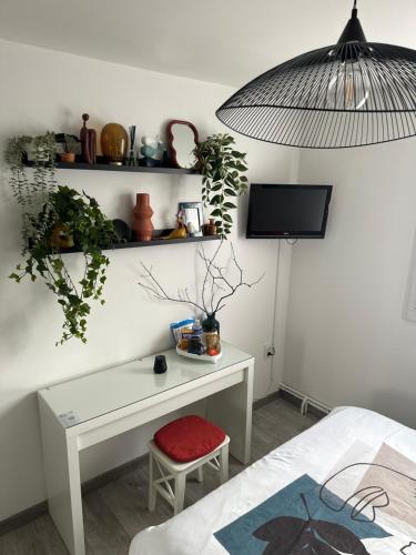 Una habitación con un escritorio, un televisor y una cama. en Cosy & Style blue forest room proche CDG AirPort, en Tremblay-en-France