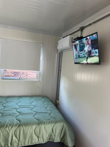 a small bedroom with a bed and a flat screen tv at Apart del Este Loft 12 in Paysandú