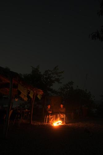 two people sitting around a fire at night at Dera Baghdarrah Nature Retreat Udaipur in Udaipur