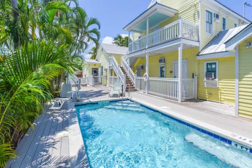 a pool in front of a yellow house with palm trees at VanGogh Studio in Key West