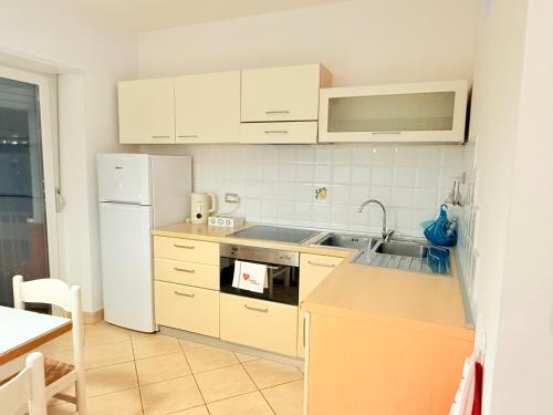 a kitchen with white cabinets and a sink and a refrigerator at Vista Rosengarten in Bolzano
