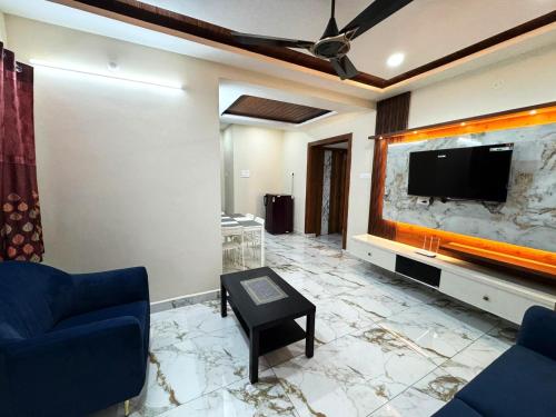 a living room with a large tv and a couch and a table at Urban Nest Homestay in Tirupati