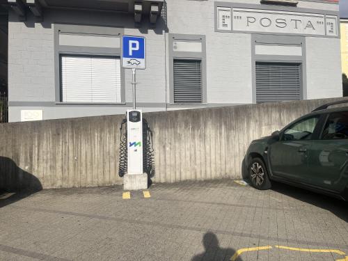 a parking lot with a parking meter in front of a fence at Court House Sonvico in Lugano