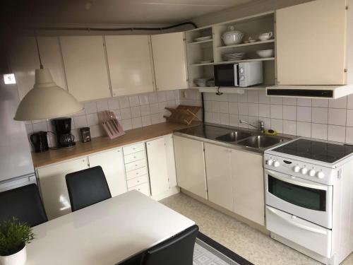 a kitchen with white cabinets and a sink and a stove at Suncity, Sunrise 2an in Borgholm