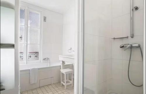 une salle de bain blanche avec une douche et un lavabo dans l'établissement Appartement proche île saint Louis, à Paris