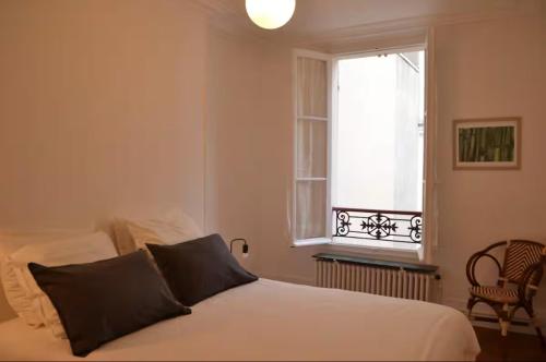 une chambre avec un lit blanc et une fenêtre dans l'établissement Appartement proche île saint Louis, à Paris