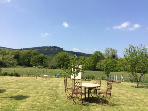 une table et des chaises assises dans un champ dans l'établissement Chambre Raphaël les monts, à Sainte-Feyre