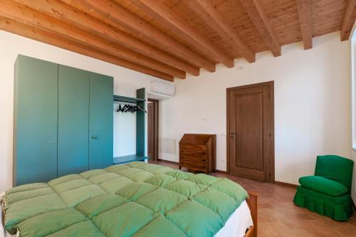a bedroom with a large green bed and a green chair at Agriturismo Cascina Tavolette in Pralboino