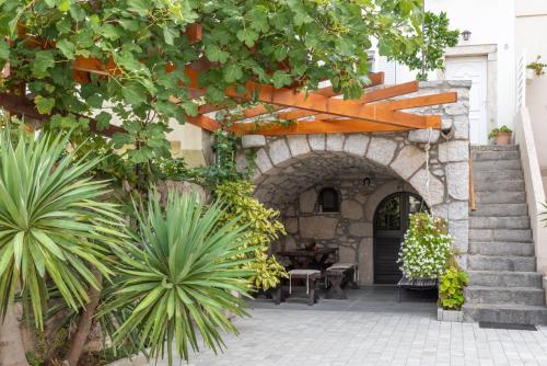 a patio with an archway and plants in front of a building at Guest house Otto in Punat