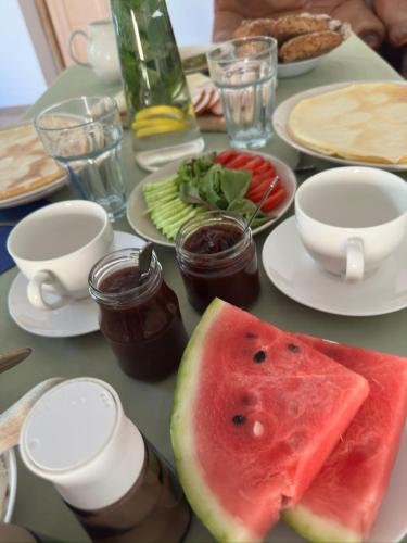 a table topped with plates of food with watermelon and jams at Pokoje Stajnia Kaliska in Łochów
