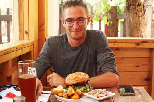 a man sitting at a table with a sandwich and chips at Cabin Resort in Moshav Ramot