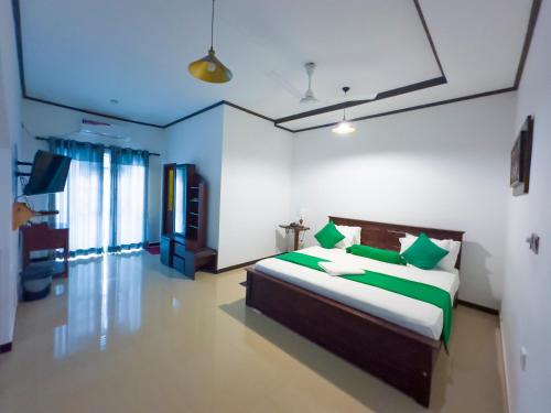 a bedroom with a bed with green and white pillows at Mount Seven Holiday Inn in Belihul Oya
