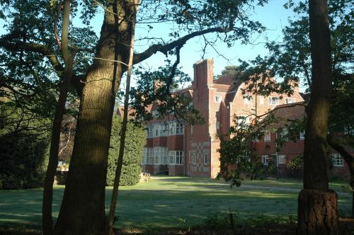 a large red brick building with trees in the foreground at Avon Tyrrell Outdoor Activity Centre in Bransgore