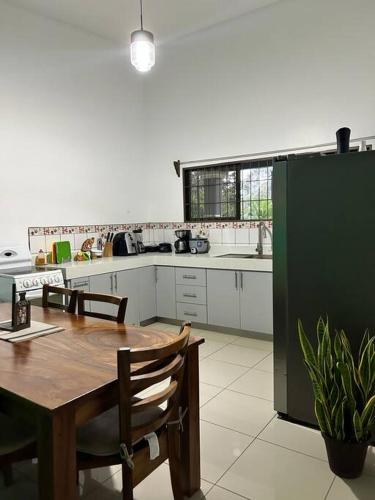 a kitchen with a wooden table and a green refrigerator at Hospedaje Santiago in Sarapiquí