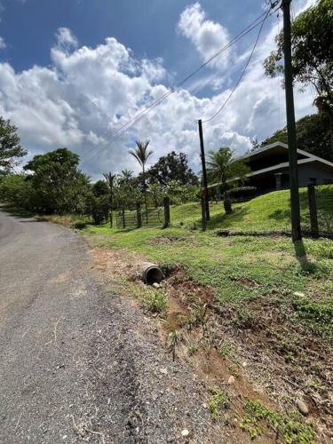 a dirt road next to a field and a house at Hospedaje Santiago in Sarapiquí