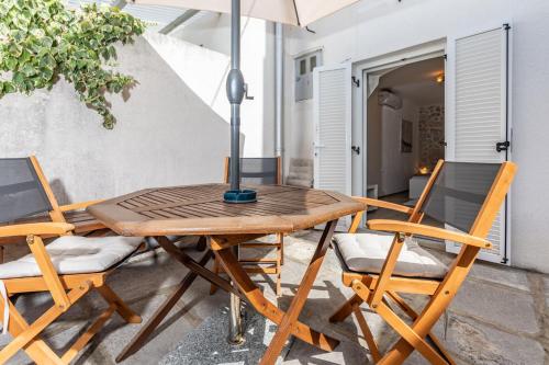 a wooden table and chairs with an umbrella on a patio at Guest house Otto in Punat