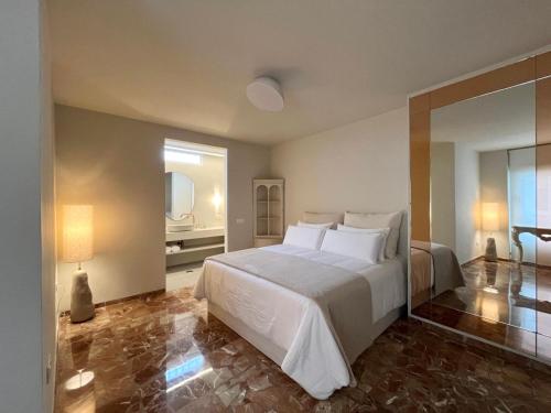 a bedroom with a large white bed and a bathroom at Jaén Delice Deluxe & Parking in Jaén