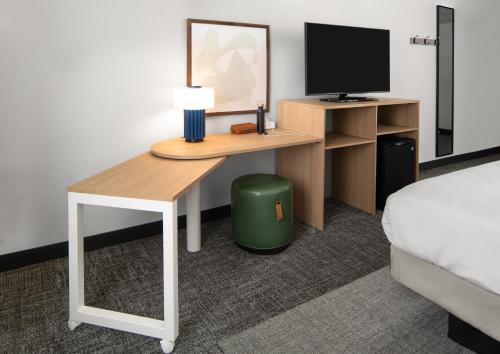 a room with a desk with a bed and a television at Spark By Hilton Hershey Near The Park in Hershey