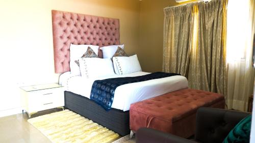 a bedroom with a large bed with a red headboard at Kebo events agro &self catering apartments in Mochudi