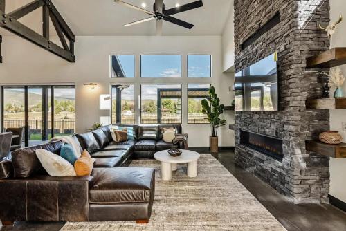 a living room with a leather couch and a brick fireplace at Hot Tub Minutes 2 ParkCity & Jodanelle Pets are Allowed in Francis