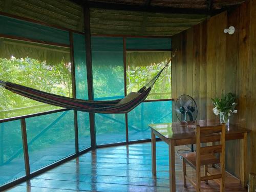 a hammock is hanging in a room with a table and chairs at Amaca Eco Station in Iquitos