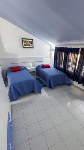 a bedroom with two beds with blue sheets and red pillows at Palazzo Nicole in Adria