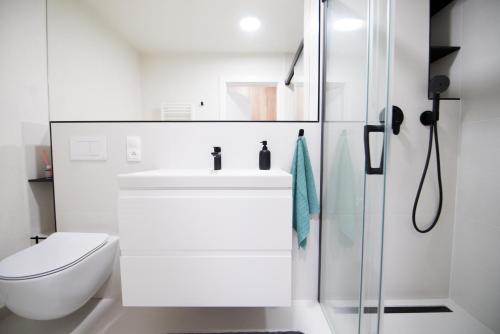 a white bathroom with a sink and a toilet at Apartmán Dominanta in Liptovský Mikuláš
