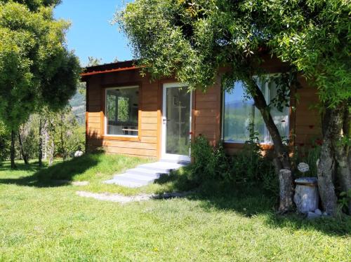 a small wooden house with a tree in the yard at Prunus Casa de Montaña in El Hoyo
