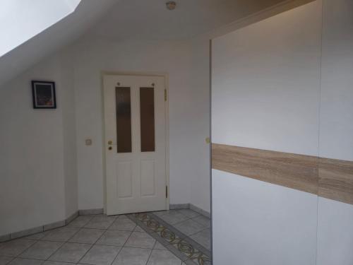 a hallway with a white door and a tile floor at Parkplätze, Einzelbetten, 2 Balkone, fast Wi-Fi 100 Mbit, Homeoffice, Aufzug, lichtdurchflutet, Panoramablick in Erlensee