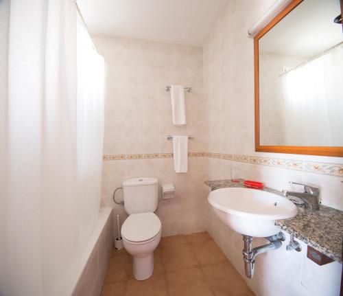 een badkamer met een toilet, een wastafel en een spiegel bij Binibeca Mar II in Binibeca