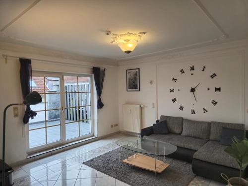 a living room with a couch and a clock on the wall at Parkplätze, Einzelbetten, 2 Balkone, fast Wi-Fi 100 Mbit, Homeoffice, Aufzug, lichtdurchflutet, Panoramablick in Erlensee