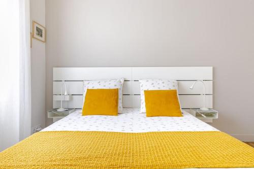 a bedroom with a bed with two yellow pillows at La Boulangerie Appartement 1 in Janzé