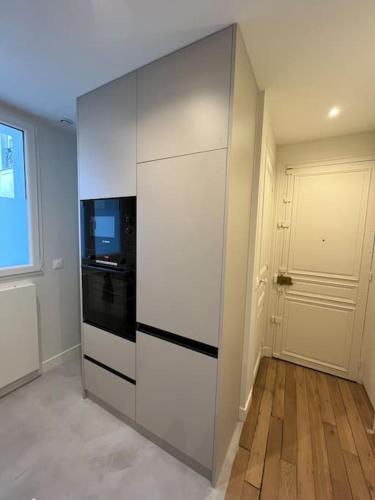 - une cuisine blanche avec cuisinière et porte dans l'établissement Appartement Paris 15 Porte de Versailles, à Paris