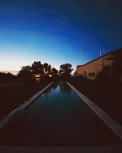 une piscine d'eau la nuit avec un bâtiment dans l'établissement Maison drôles d'oiseaux, à Plieux
