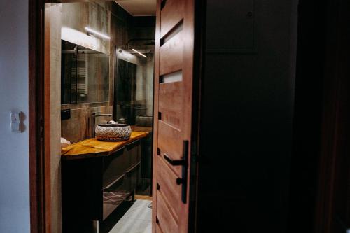 a bathroom with a sink and a wooden door at Apartament Madlen Art in Olecko