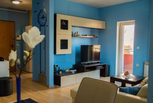 een woonkamer met blauwe muren en een tv bij Apartment Giro in Zagreb