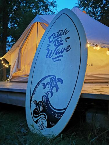 a surfboard with a wave on it next to a tent at Pokoje Stajnia Kaliska in Łochów
