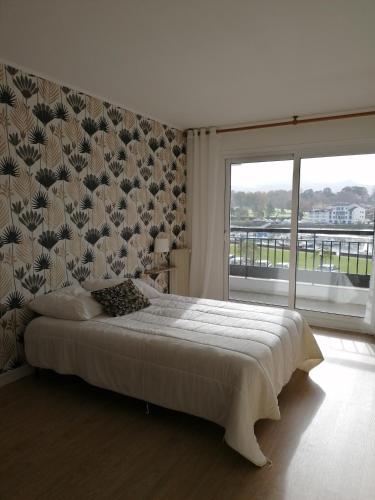 une chambre avec un grand lit et une grande fenêtre dans l'établissement Grand appartement avec vue - Plage à pied, à Saint-Jean-de-Luz