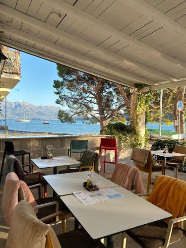 a restaurant with tables and chairs and a view of the water at Portico Djenovici in Ðenovići