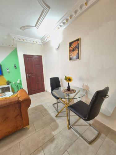 a living room with a glass table and chairs at Happy Holidays studios meublés à Yaoundé Nkozoa non loin du stade Olembé in Yaoundé