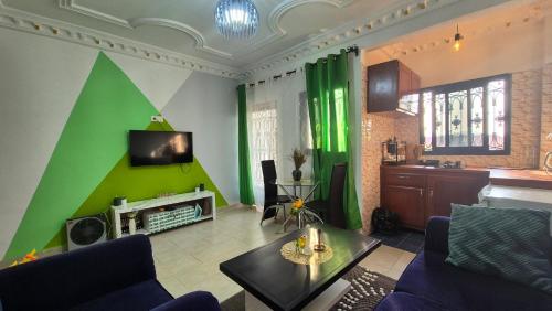 a living room with a green accent wall at Happy Holidays studios meublés à Yaoundé Nkozoa non loin du stade Olembé in Yaoundé