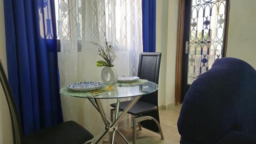 a glass table with a vase on it in a room at Happy Holidays studios meublés à Yaoundé Nkozoa non loin du stade Olembé in Yaoundé