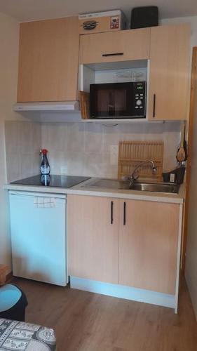 une petite cuisine avec un évier et un micro-ondes dans l'établissement Appartement vu sur la montagne, à Le Biot