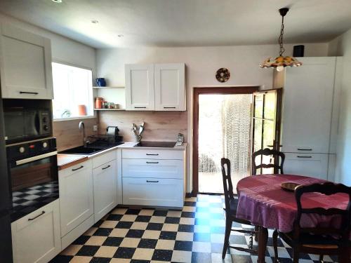une cuisine avec des placards blancs et une table avec un chiffon de table dans l'établissement Maison de charme près de la mer, à Bormes-les-Mimosas