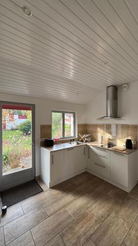 une grande cuisine avec des armoires blanches et une fenêtre dans l'établissement Gîte La Grange de Pardies, à Orthevielle