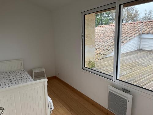 Cette chambre comprend un lit et une grande fenêtre. dans l'établissement Maison de campagne - proche Bordeaux, à Saint-Vincent-de-Paul