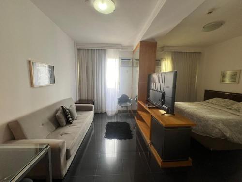 a hotel room with a couch and a tv and a bed at Flat Piemonte in Nova Lima