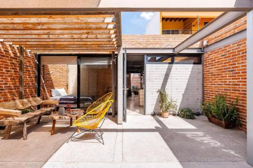 a patio with a yellow chair and a couch at Casa Franco - Modern Architecture Home with AC in San Miguel de Allende